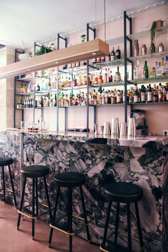 Sur tout un pan du mur tapissé de vieux rose, les potions des bartenders sont exposées.
