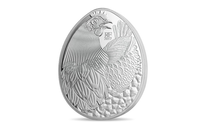 Monnaie en forme d’oeuf. Une poule composée de différents éléments culinaires, comme l’artichaut et la truffe, est présente sur la face de cette monnaie.