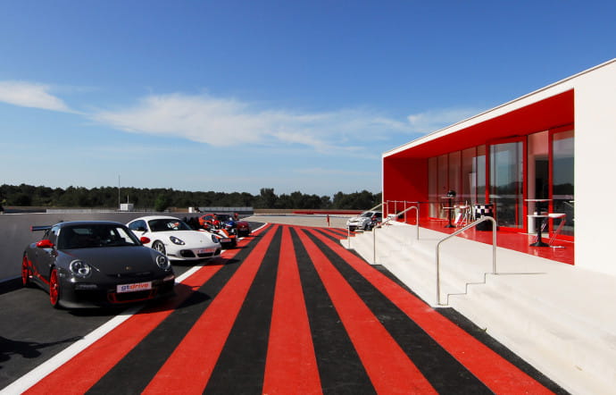Architecture 54 a ajouté une piste supplémentaire pour l’école de pilotage, le Driving Center, construit en porte‑à‑faux sur un double emmarchement en béton.