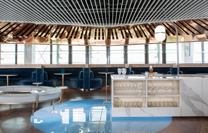 Signé du designer atypique Mathieu Lehanneur, le bar du nouveau salon Business d’Air France est un lieu chic et immersif, jouant sur le bois, le marbre, le miroir et la lumière. Le bar central est entouré de loges tapissées de velours confortables et connectées.