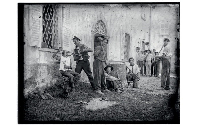 Groupe d’hommes devant un bâtiment, 1900-1932.