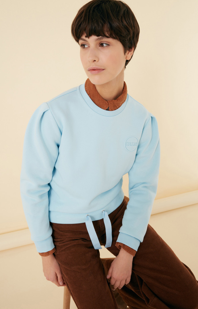Colmar revisite le sweatshirt dans une version qui met l’accent sur sa taille : serrée à l’aide d’un lacet large, elle la marque et donne à la silhouette un esprit plus moderne. 129 €.