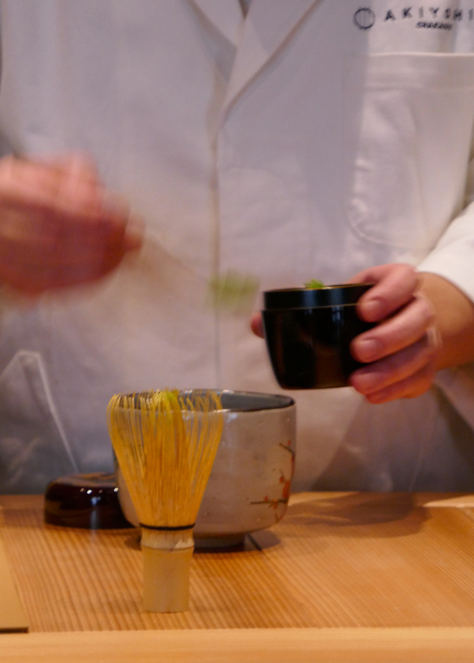 Avec un « chashaku », fine spatule en bambou, Yuichiro Akiyoshi récupère quelques grammes de poudre de thé matcha conservé dans un « natsume », petite boîte en bois laqué, et les dépose dans un bol « chawan » (céramique japonaise artisanale) avant de mélanger avec « shasen » petit fouet aux brins.