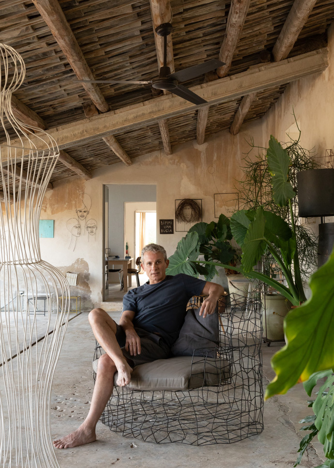 Le designer Antonino Sciortino, assis sous le portique de sa maison parmi plusieurs de ses œuvres en fil de fer, dont certaines sont des prototypes.