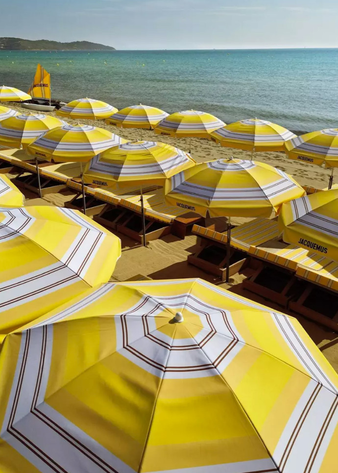 Parasols, transats et planches de paddle à rayures jaunes soleil, blanc et bleues s’installent sur la nouvelle plage Jacquemus.