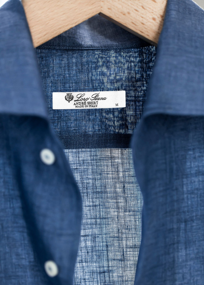 L’artiste et peintre suisse André Piot, réputé pour ses expressions graphiques et ses œuvres à l’encre de Chine, se fait confectionner une chemise en denim avec un col à larges revers repliés.