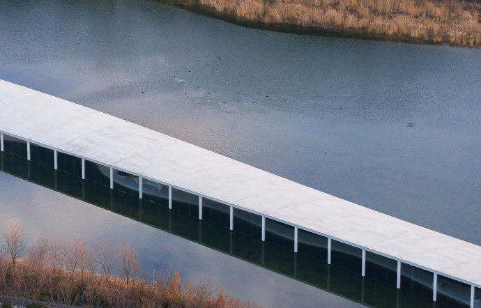 Le sol du bâtiment s’élargit, allant de 5 mètres, à l’extrémité est, jusqu’à 20 mètres, à l’ouest, pour rejoindre un second bâtiment courbe qui prend place sur une terre sèche voisine du lac.