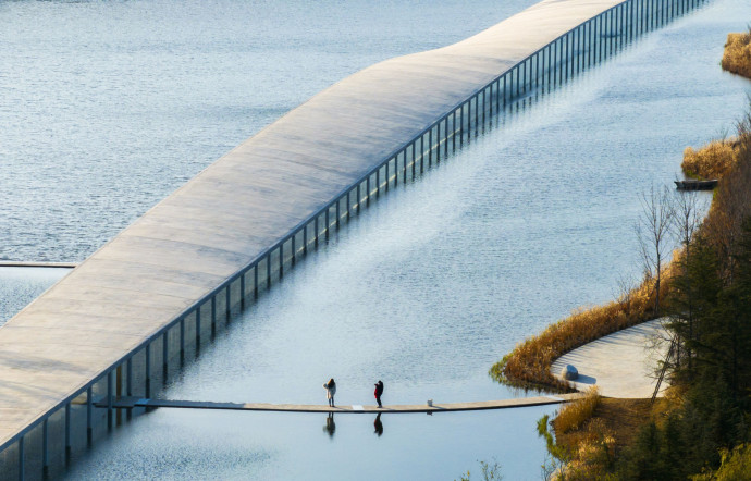 Junya Ishigami donne naissance à une construction de un kilomètre de longueur, soit peu ou prou celle du lac : une ligne franche qui le traverse d’une rive à l’autre.