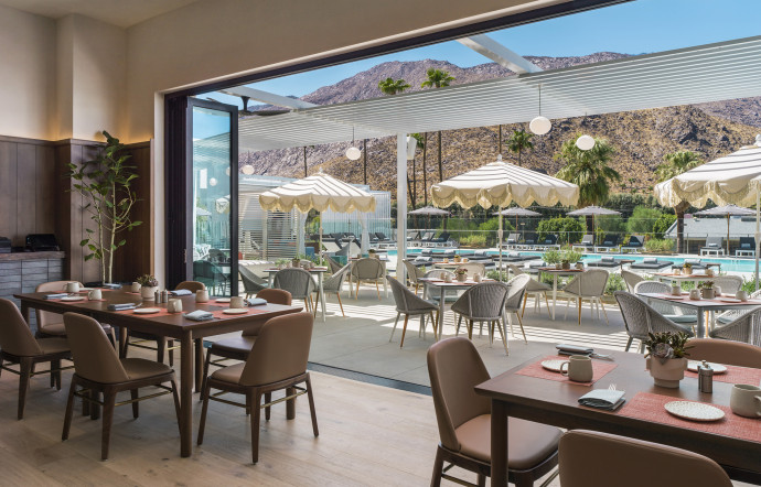 La piscine se dessine par les baies vitrées du restaurant.