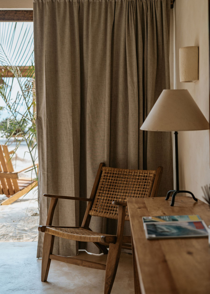 Intérieur et extérieur se fondent dans la chambre qui ouvre sur un jardin privé avec sable et transats.